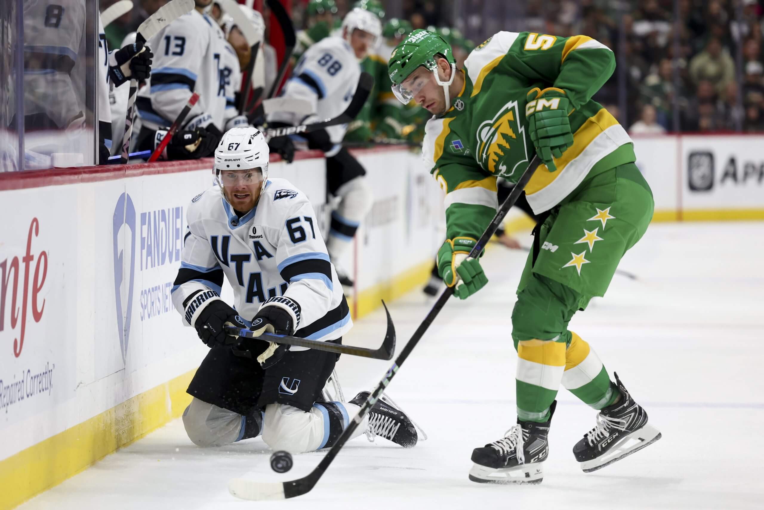 David Jiricek and a kneeling Lawson Crouse of Utah compete for a bouncing puck.