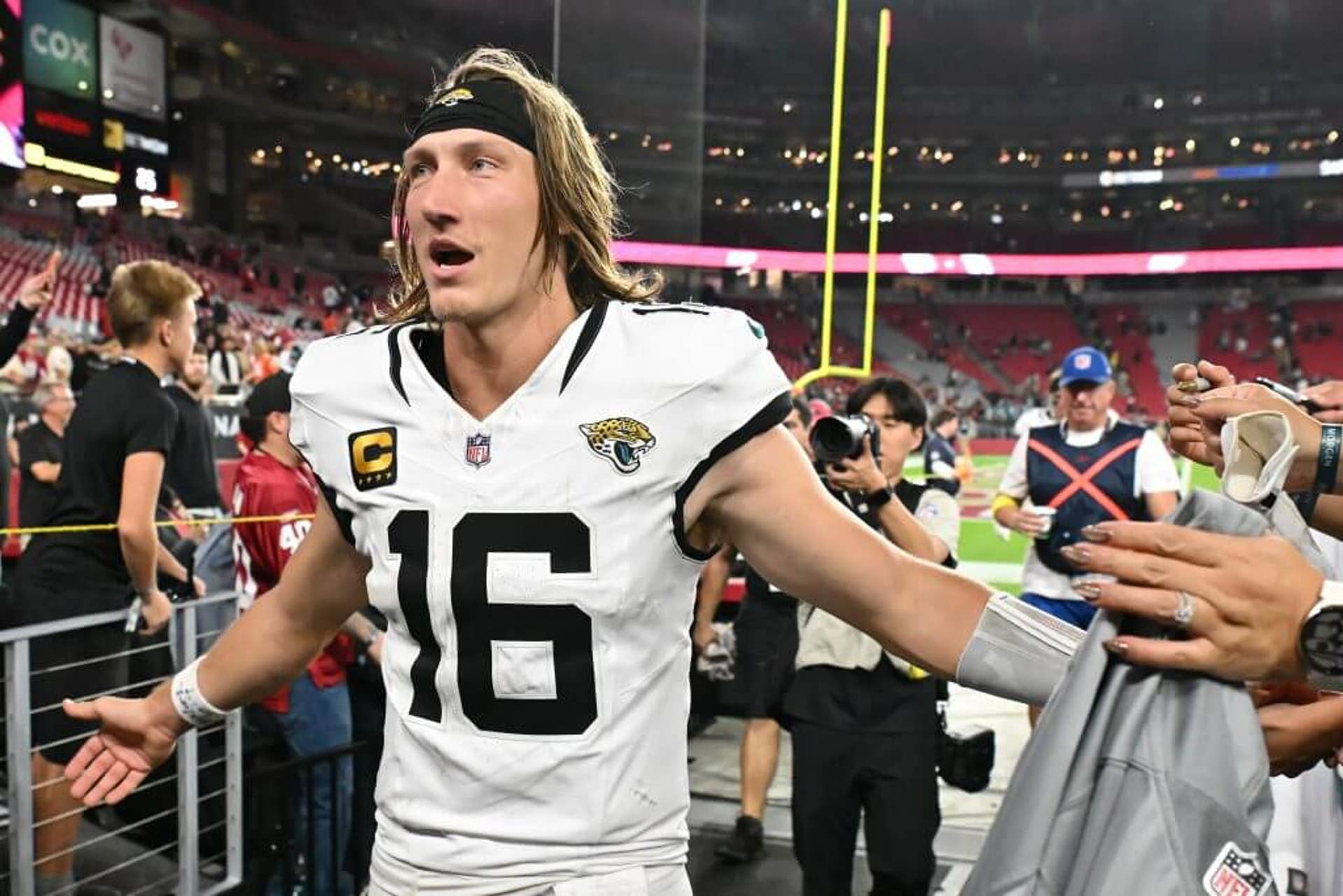 Trevor Lawrence #16 of the Jacksonville Jaguars walks off the field slapping hands with fans following the overtime game against the Arizona Cardinals at State Farm Stadium.