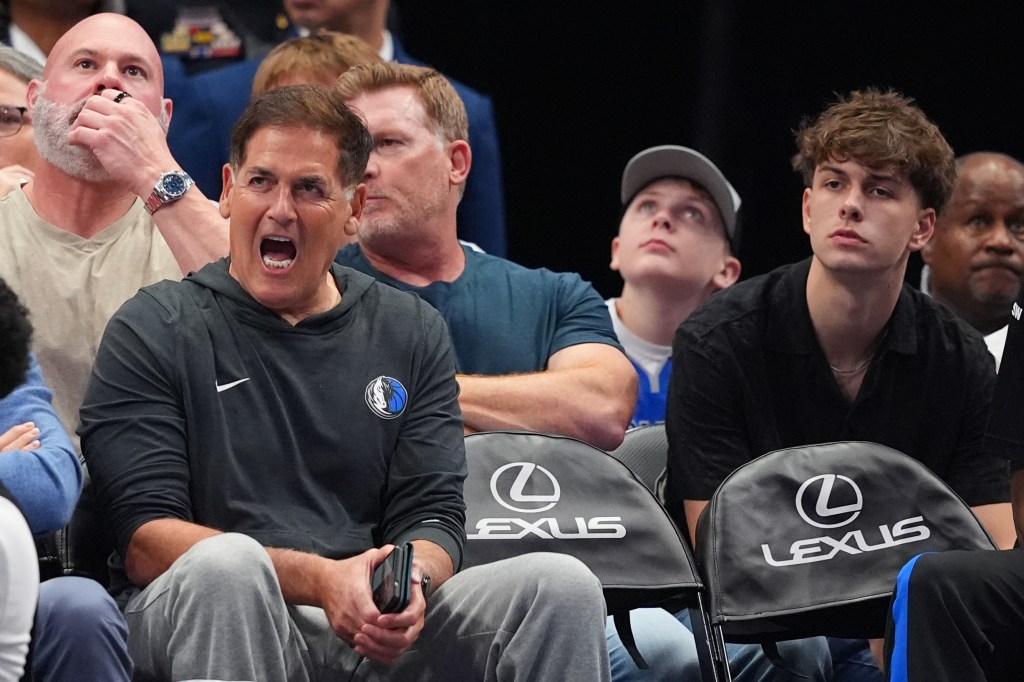 Mark Cuban reacting during a basketball game, seated in the stands.