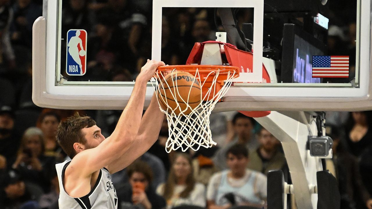 San Antonio Spurs center Luke Kornet dunks the ball against the Washington Wizards during the first half of an NBA basketball game in San Antonio, Thursday, Dec. 18, 2025. (AP Photo/Billy Calzada)