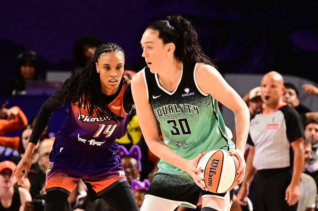 New York Liberty's Breanna Stewart holding a basketball while being guarded by a Phoenix Mercury player.