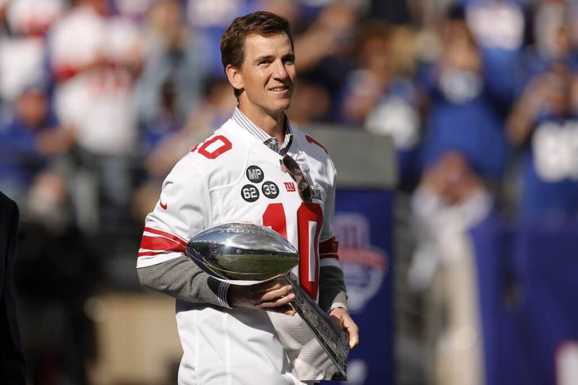 Eli Manning walks onto the field carrying the Vince Lombardi Trophy during a ceremony honoring the 2011 team.