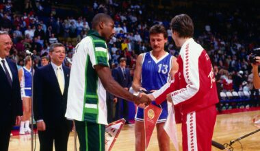 Basketball players from different teams shake hands at center court while officials and other players observe during a pre-game ceremony.