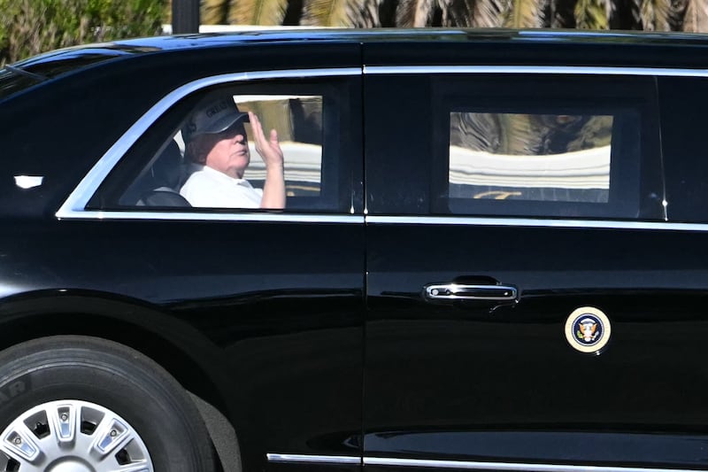 President Donald Trump waves from his motorcade as he returns to his Mar-a-Lago club from Trump International Golf Course in Palm Beach, Florida, on December 22, 2025.