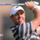 Rory McIlroy watches his shot as he holds a club above his head