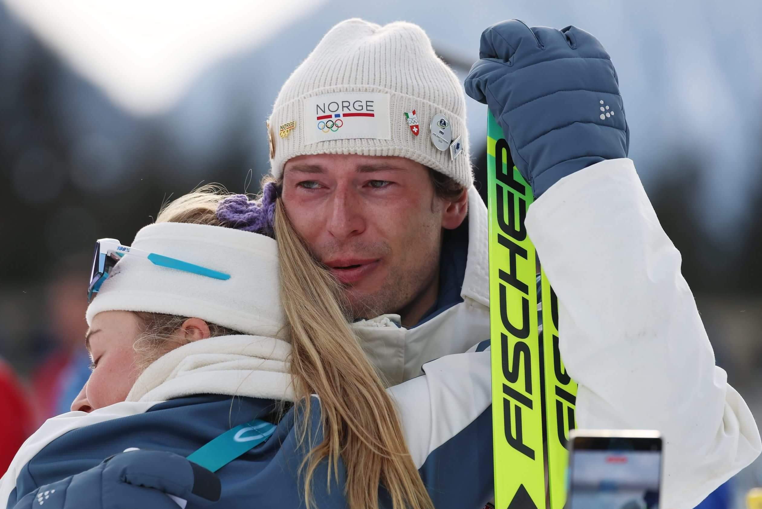 Sturla Holm Laegreid is hugged by teammate Ingrid Landmark Tandrevold after the medal ceremony. 
