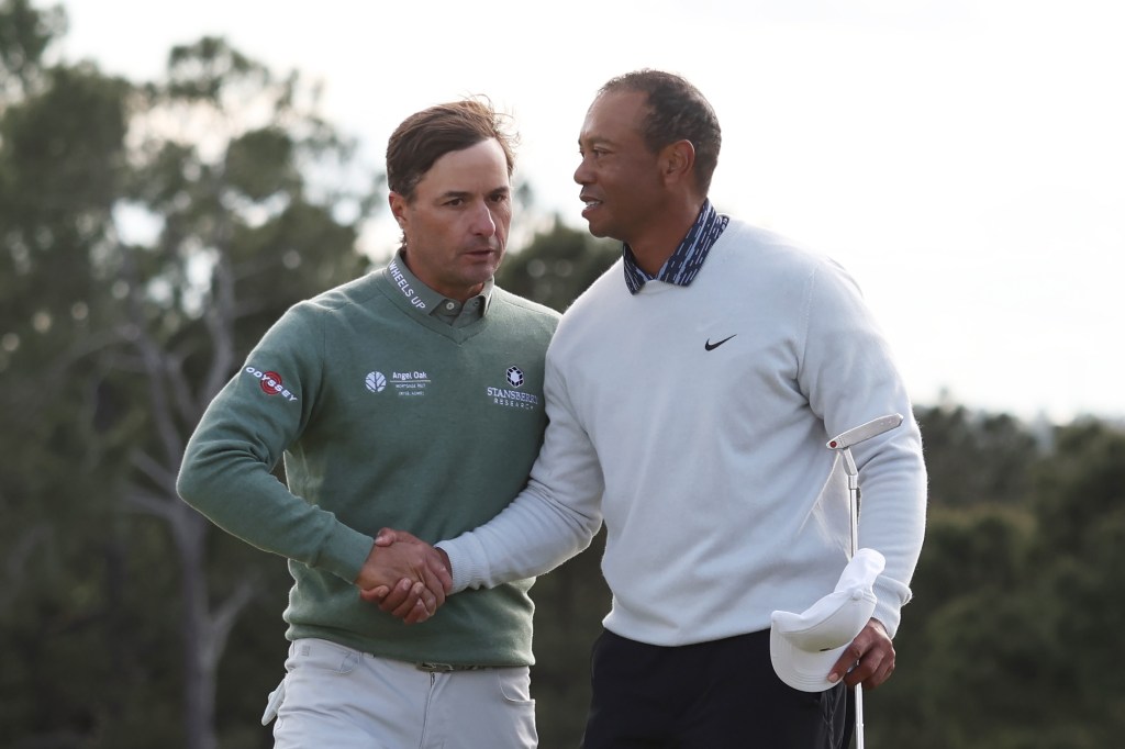 Two male golfers, one in green and one in white, shake hands on a golf course.