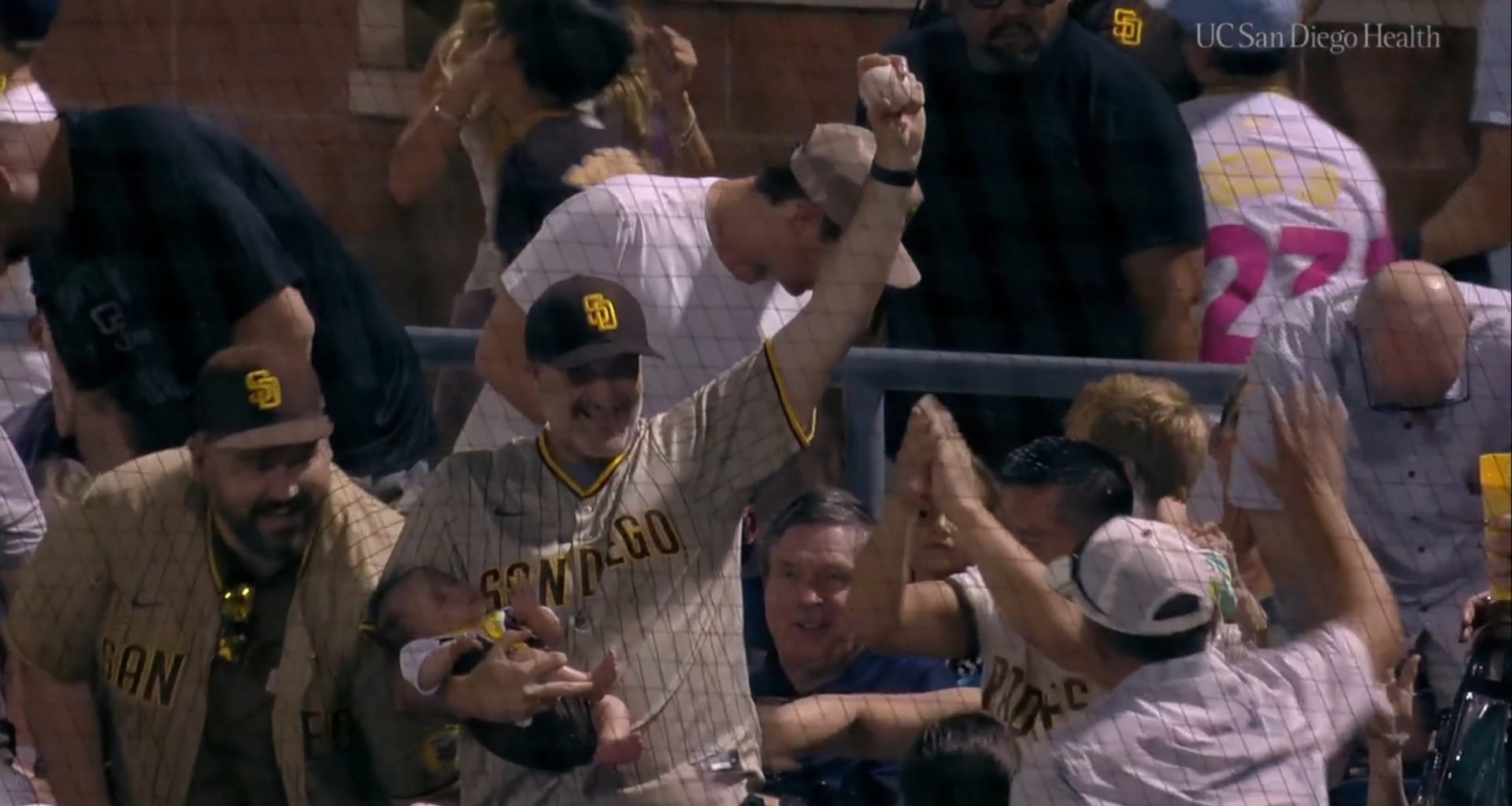 Fan makes a nifty bare-handed catch while holding a sleeping baby