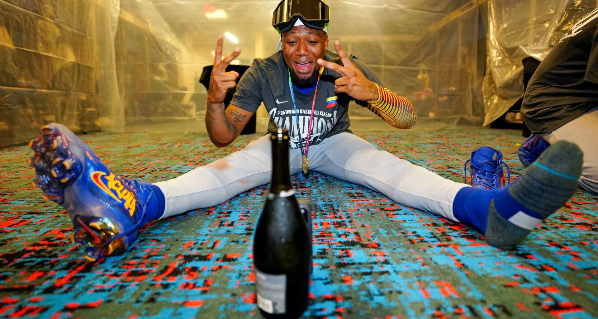 Ronald Acuña Jr. celebrating Venezuela's World Baseball Classic title by himself in the clubhouse, using a champagne bottle to prop his phone up
