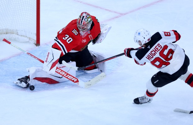 Blackhawks goaltender Spencer Knight blocks a shot by Devils center Jack Hughes in the second period Nov. 12, 2025, at the United Center. (Chris Sweda/Chicago Tribune)