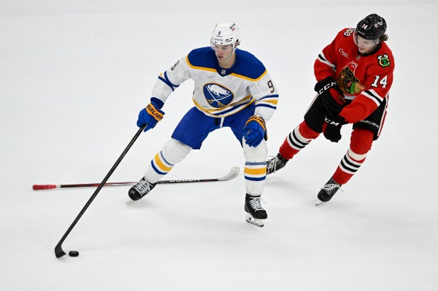 The Blackhawks' Kevin Korchinski battles for a loose puck against the Sabres' Josh Norris on April 13, 2026, at the United Center. (AP Photo/Paul Beaty)