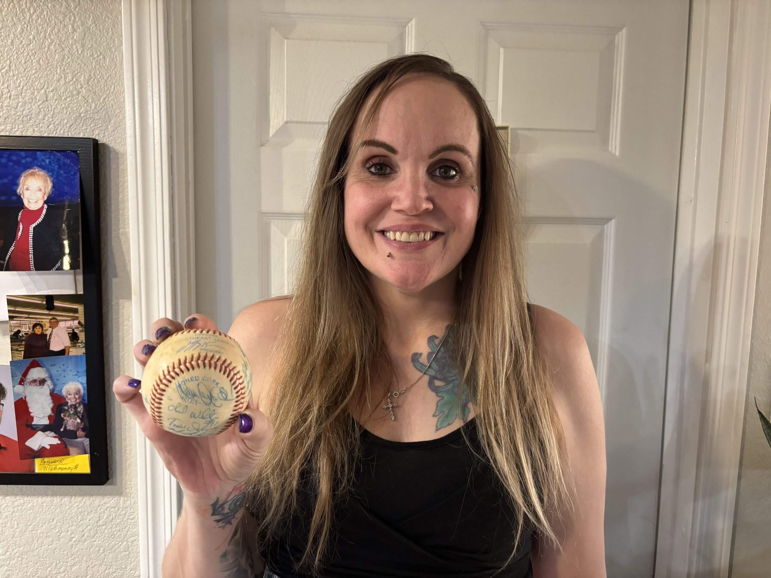 Marissa MacDougall Johnson holds up a ball signed by Dennis "Oil Can" Boyd and other members of the Bangor Blue Ox.