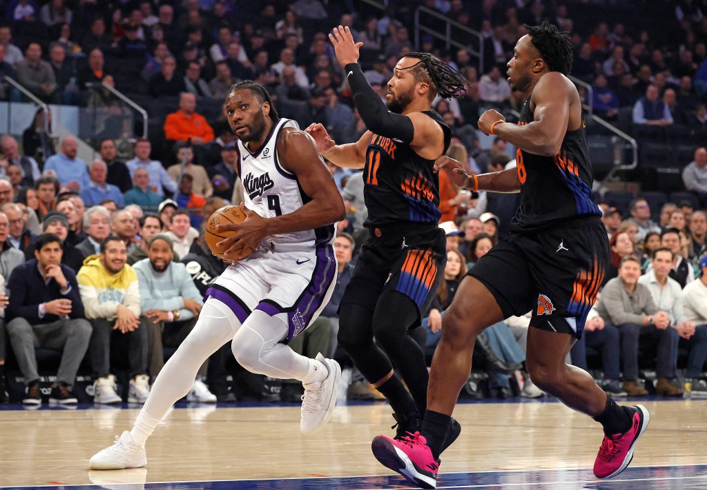 Sacramento Kings player Precious Achiuwa drives to the basket as New York Knicks players Jalen Brunson and OG Anunoby give chase.