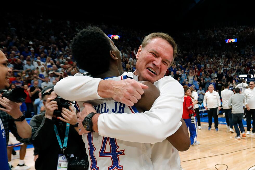 Kansas guard Melvin Council Jr. (14) is hugged by Kansas head coach Bill Self, right, as they...