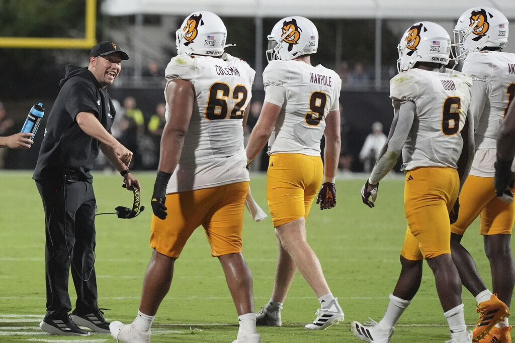 Arizona State head coach Kenny Dillingham, left, confers with his players during the second half of an NCAA college football game against Mississippi State in Starkville, Miss., Saturday, Sept. 6, 2025. (AP Photo/Rogelio V. Solis)