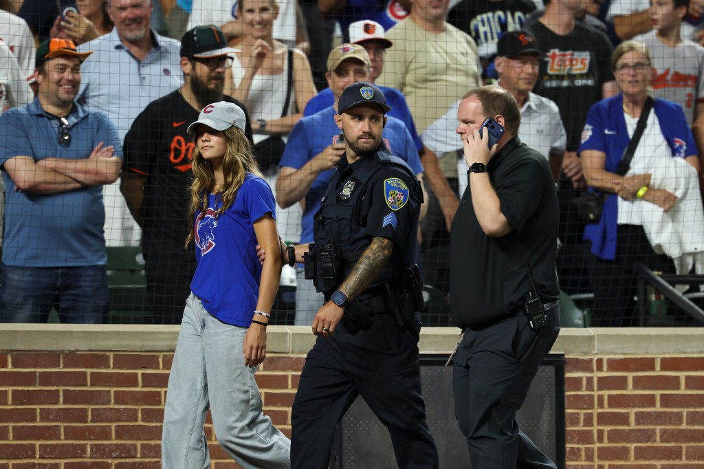 A fan is escorted off the field by police and security after entering the field during the ninth inning a baseball game between the Baltimore Orioles and the Chicago Cubs, Wednesday, July 8, 2026, in Baltimore.