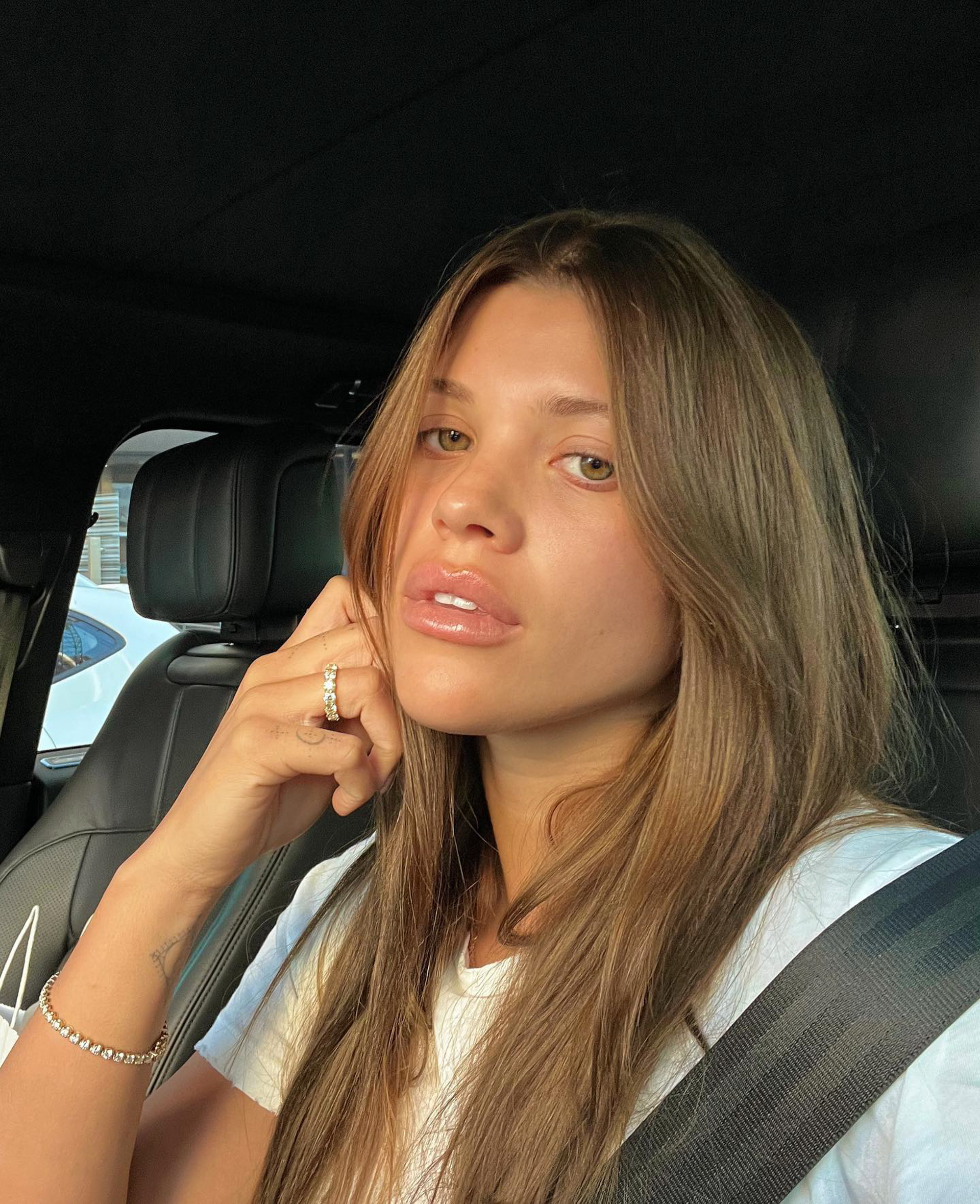 A woman in a car wearing a diamond tennis bracelet.
