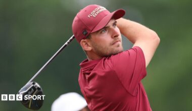 Jack Whaley, in red golf shirt and cap, tees off and watches his shot