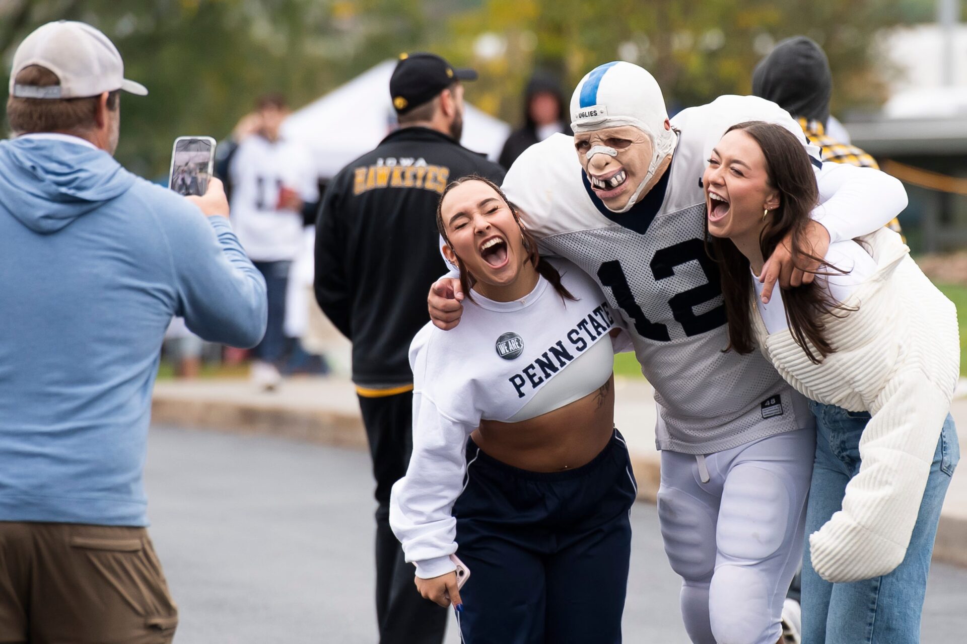A pair of Penn State fans pose for a photo with one of the three famous \"Big Uglies\" outside Beaver Stadium before the start