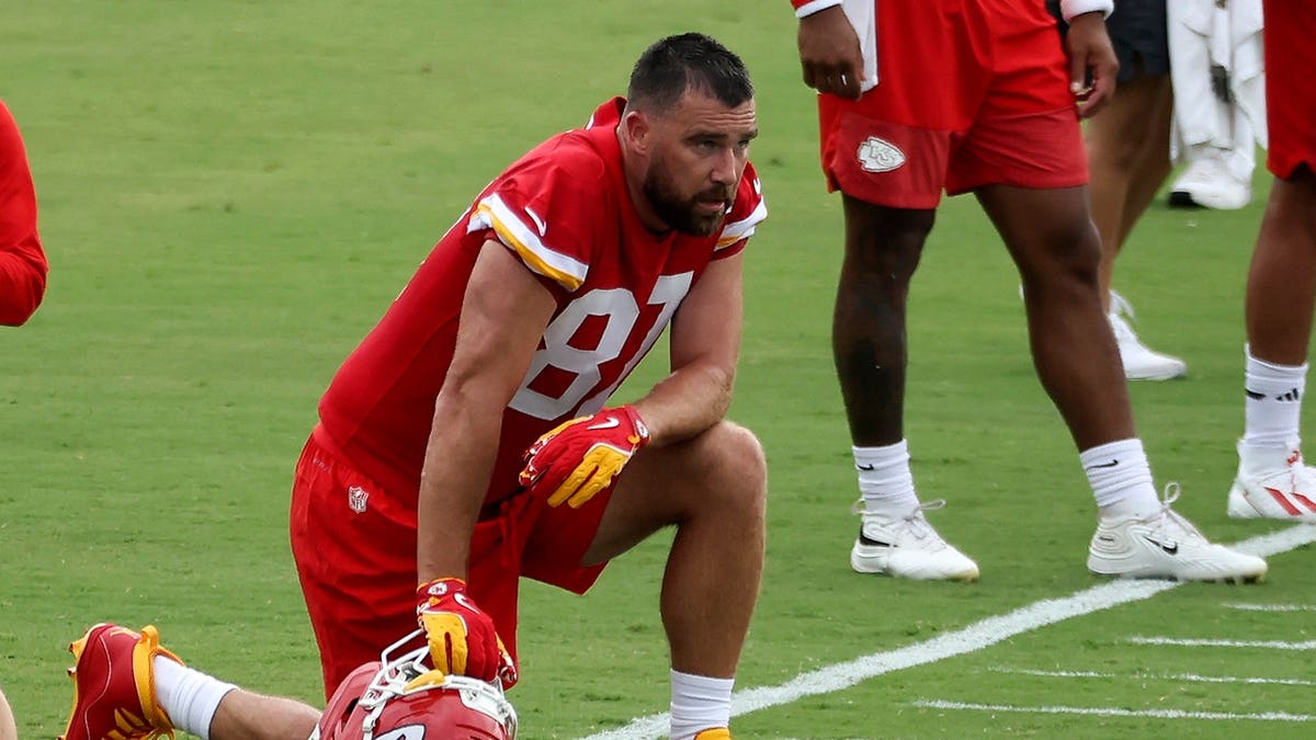 Travis Kelce kneels on the sideline during Kansas City Chiefs training camp.