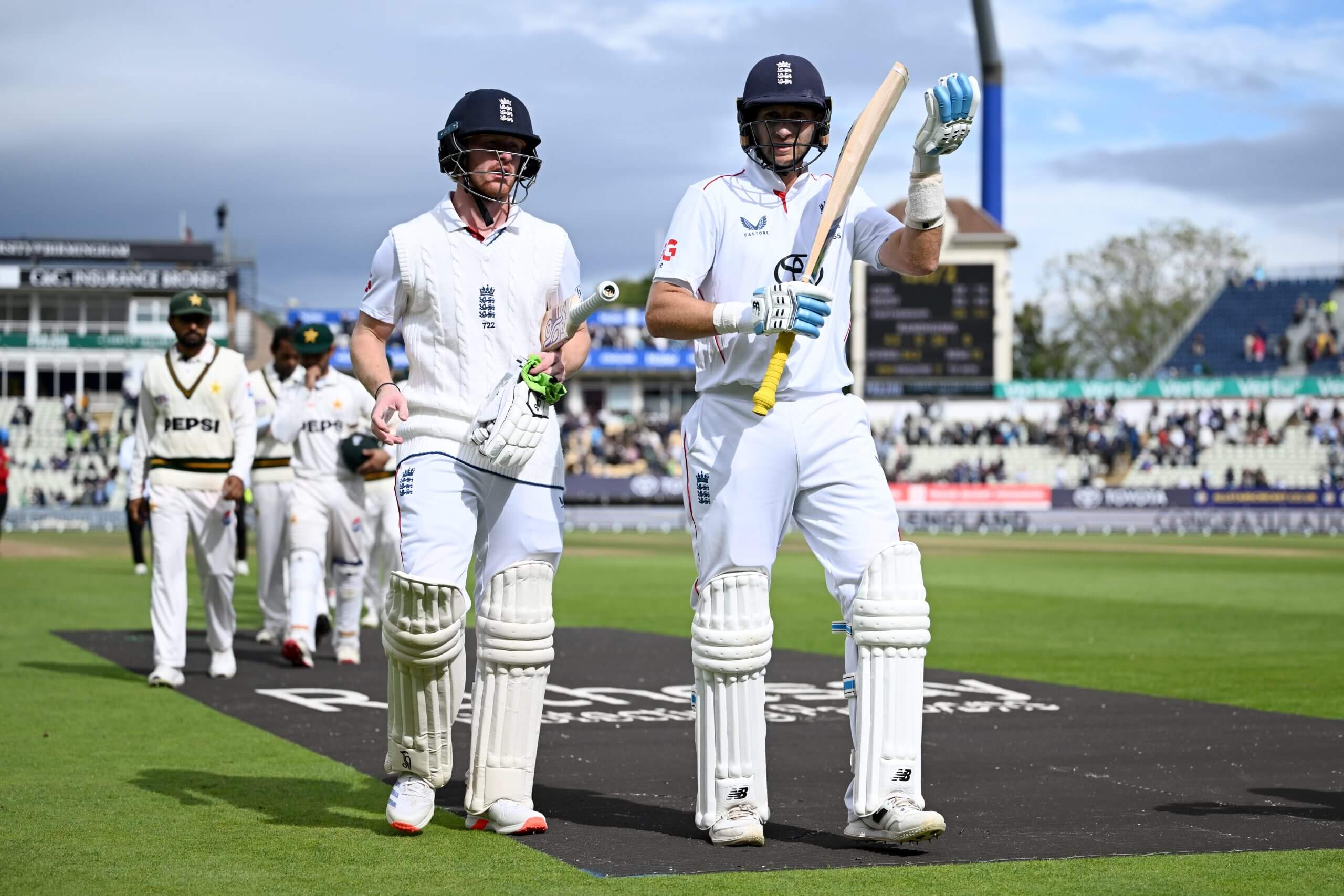 Jordan Cox and Joe Root lead the players from the pitch after England's victory