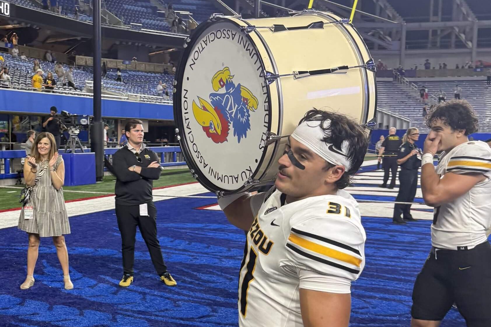 Anthony Favrow carries a drum on his shoulder with the Kansas Jayhawk logo on one side