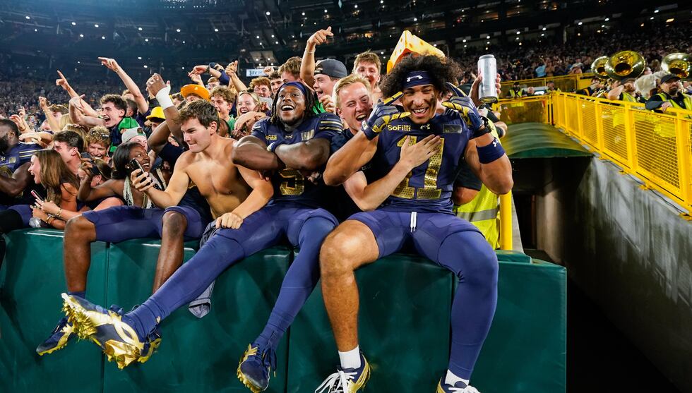 Notre Dame players celebrate with fans after winning against Wisconsin in an NCAA college...