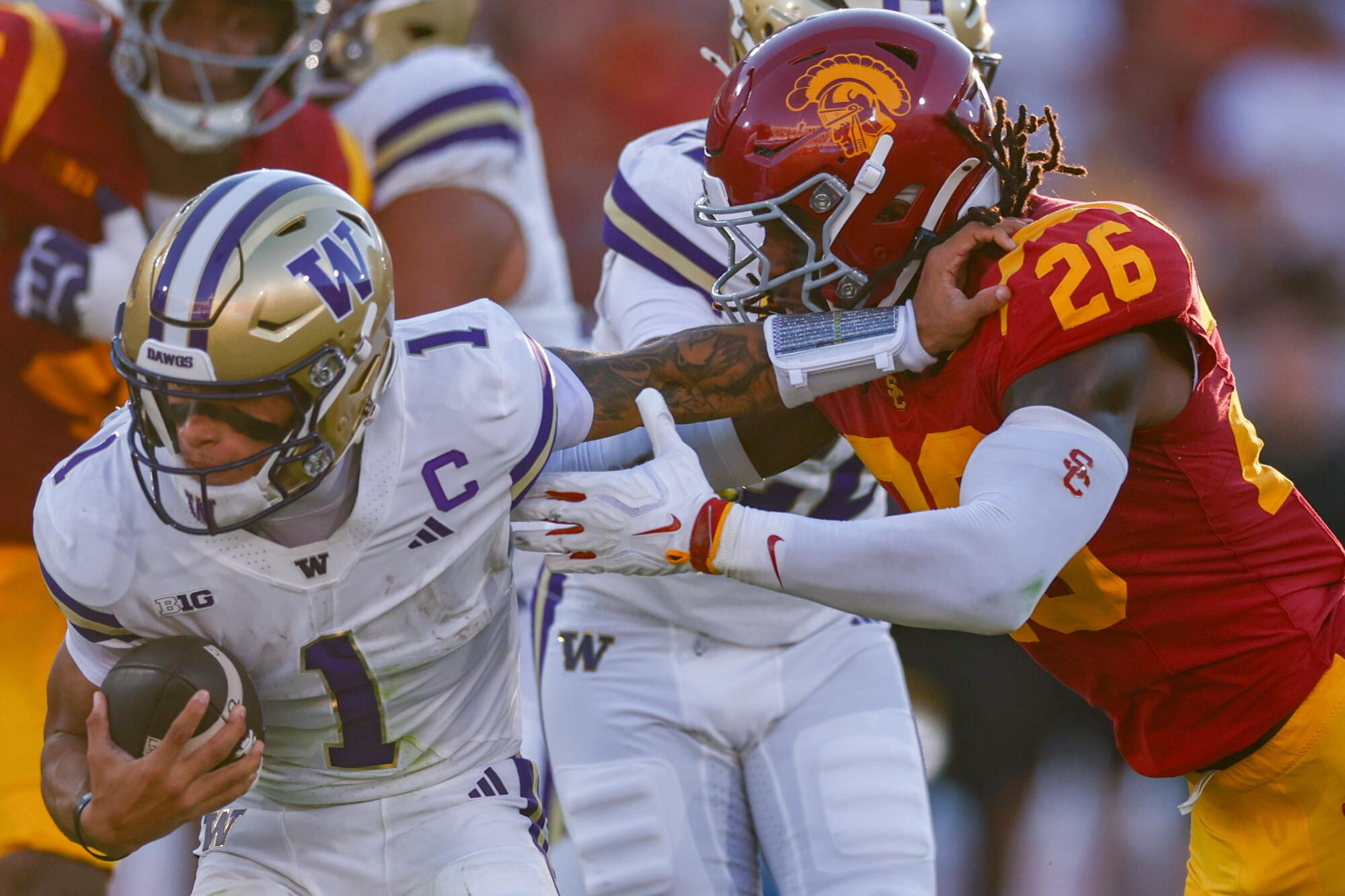 Washington quarterback Demond Williams Jr., left, tries to fend off USC linebacker Elijah Newby.