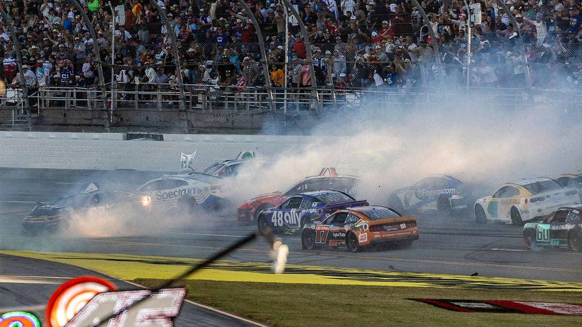 A major wreck occurs on the track approaching the finish line during a NASCAR race at Talladega Superspeedway.